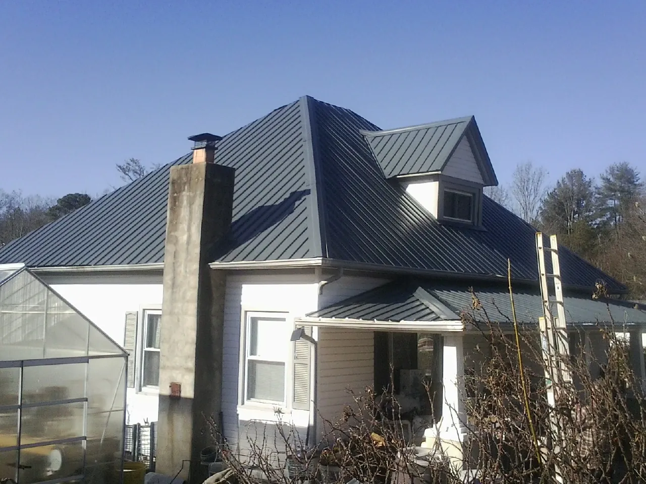 Dark blue standing seam metal roof on a white farmhouse with dormer — Slate & Tile Roof Repair by Roofing Brothers in Drain