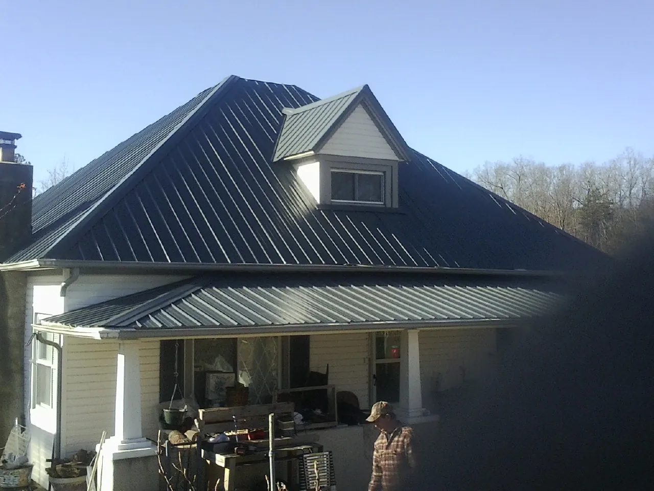Dark blue standing seam metal roof with a dormer above a front porch in Drain