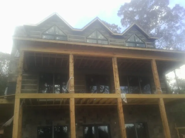 Dormers and porch framing on a large log home under construction — Roof Coating work by our crew in Drain