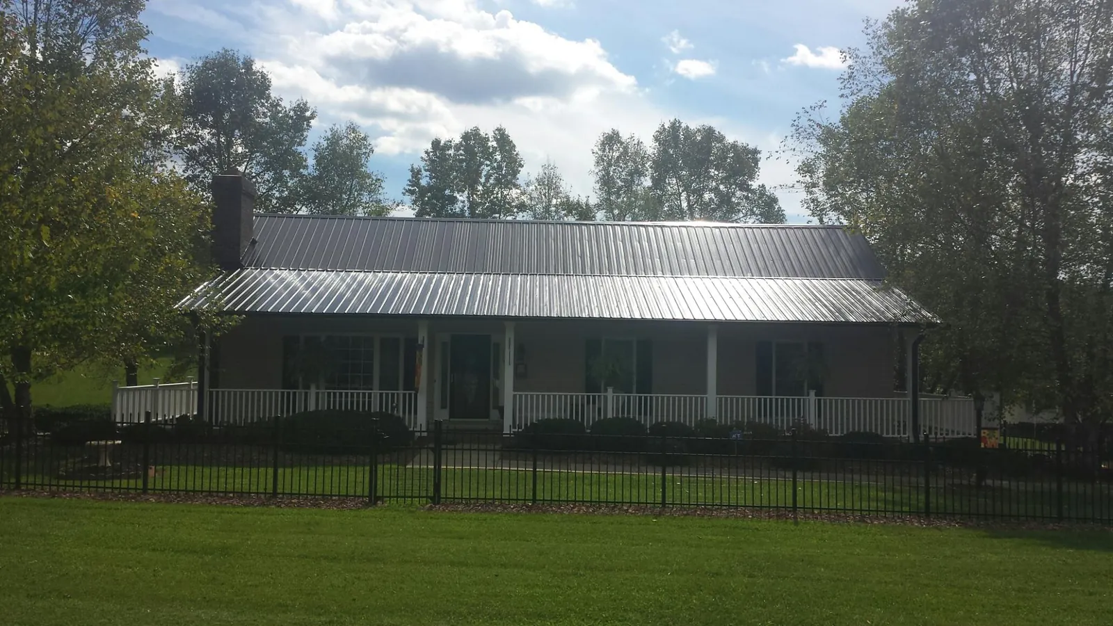 Gray metal roof on a brick ranch with a full width front porch — Gutter Guard Installation work by our crew in Drain