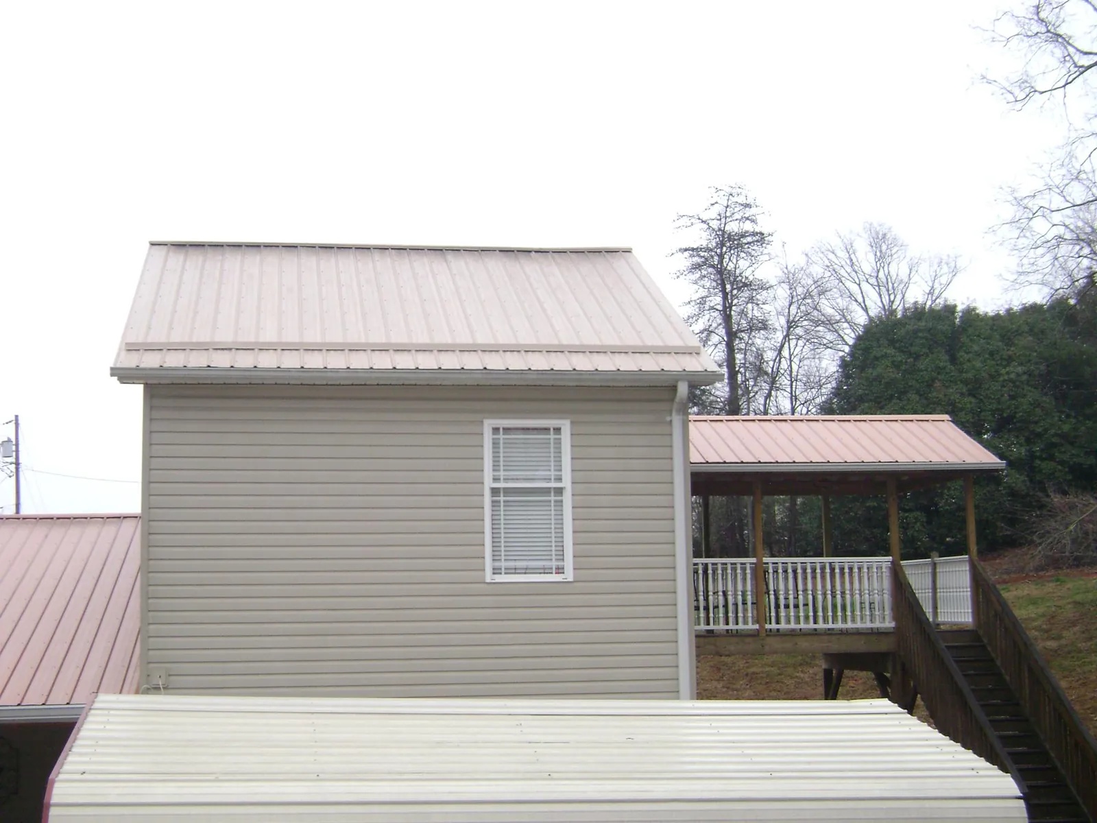Tan metal roofs on a two story addition and attached porch, from a Roof Replacement job in Drain